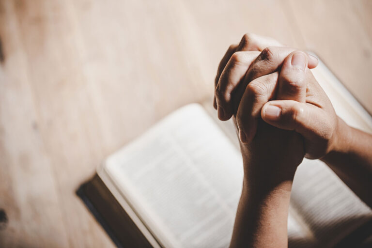 Hands Praying over a religious Book